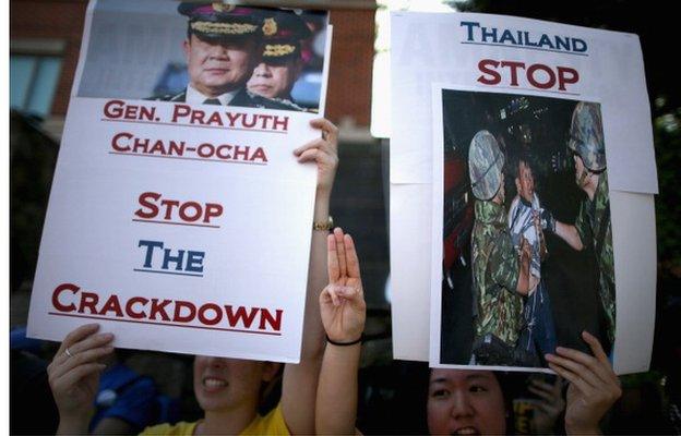 Flashing a three-finger salute borrowed from the 'Hunger Games' sci-fi fantasy books and movies, demonstrators from Amnesty International rally against the military crackdown on opposition protests and free speech in Thailand outside the Royal Thai Embassy 5 June 2014 in Washington, DC.