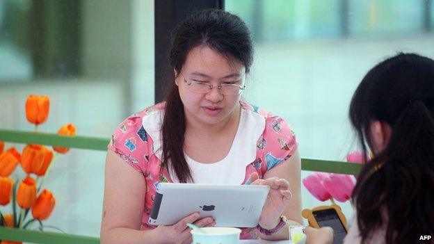 Women use portable devices to browse the Internet in a restaurant in Haikou, south China's Hainan province