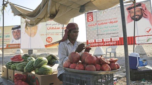 An Asian vendor waits for costumers in front of a election campaign posters of Saif Saeed al Jeneed, right, Saad Sultan, centre, and Khalid Ibrahim, left, in Hamad Town, Bahrain