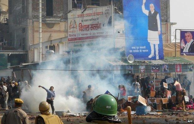 Indian security officials look on as a supporter of Rampal throws a stone in Hisar some 175kms north of New Delhi on November 18, 2014,