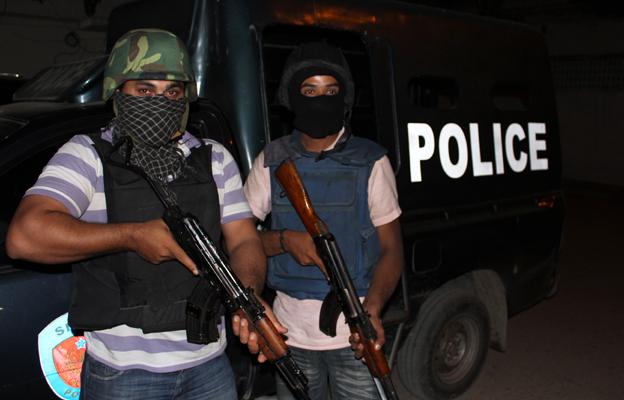 Masked and armed police officers next to a police van in Karachi preparing for a raid