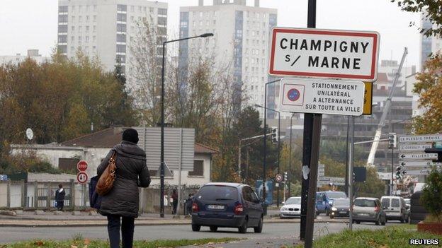 A local resident walks past a road sign at the entry of Champigny-sur-Marne, east of Paris, 19 November 2014.