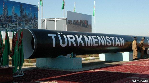 Two workmen stand next to the symbolic first piece of a gas pipeline to China outside of the city of Turkmenabat, 30 August 2007