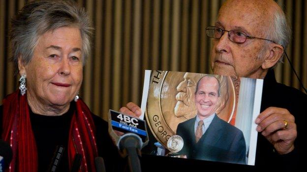 Juris Greste (R) displays a picture of his son, jailed Australian Al-Jazeera journalist Peter Greste, next to his wife Lois (L) during a press conference in Brisbane on June 24, 2014.