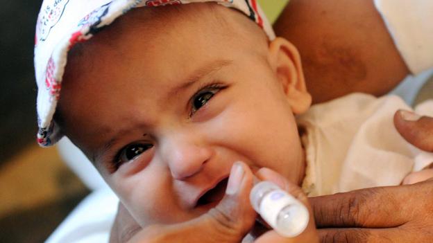 A Pakistan health worker gives polio vaccine drops to a child in Peshawar, 2012