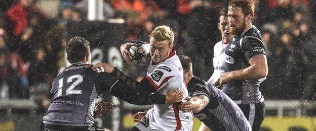 Ospreys tacklers halt the run of Ulster full-back Stuart Olding in the Belfast rain