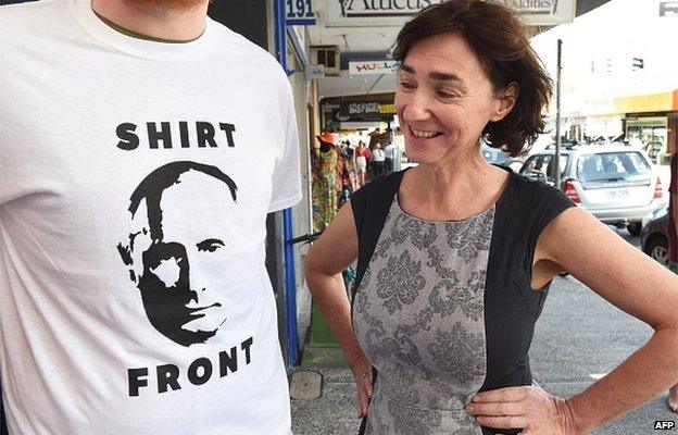 Fiona Stager (R) inspects a t-shirt her shop will give away for a donation featuring Russia's President Valdimar Putin and a quote from Australia's Prime Minister Tony Abbott threatening to 'shirt front' Putin - an Australian sporting term - when the two leaders meet at the G20 Leader's Summit in Brisbane on 13 November 2014.