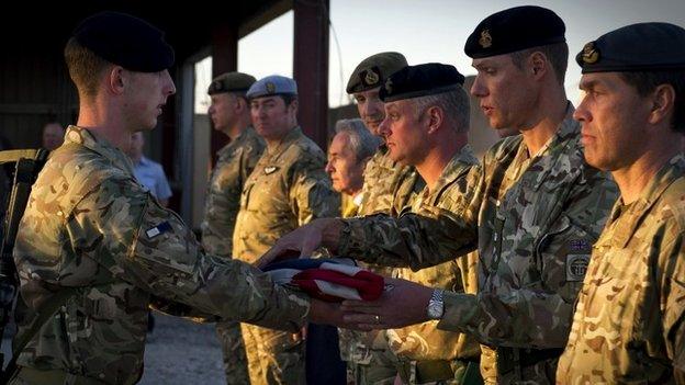 Signaller Jason Fleck presenting the Union Flag to Commander JFSp Brigadier Darrell Amison at Kandahar Air Base, Afghanistan