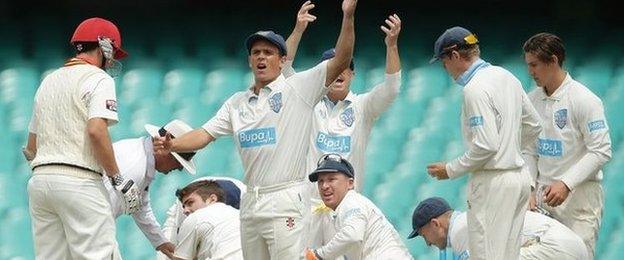 Players surround Hughes on the pitch in Sydney