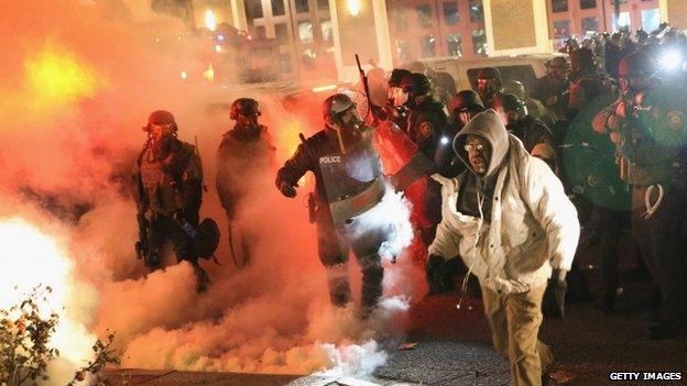 Police guard the Ferguson police department as rioting erupts following the grand jury announcement in the Michael Brown case on November 24, 2014