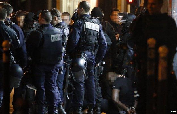 One of the two alleged robbers who attempted to rob a Cartier jewellery store on the Champs-Elysees sits on the ground after surrendering to French police forces in Paris 25 November 2014