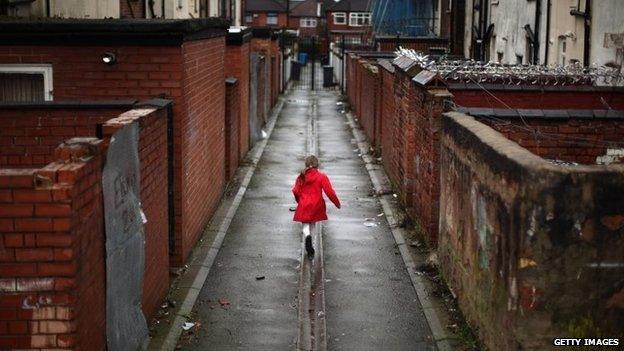 Back alley of terraced housing with girl walking in red coat