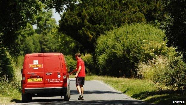 A postman returns to his Royal Mail delivery vehicle