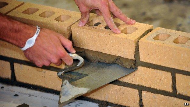 Close-up of hands laying bricks