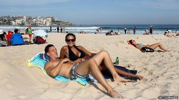 A couple enjoy the sun on Bondi Beach in Australia