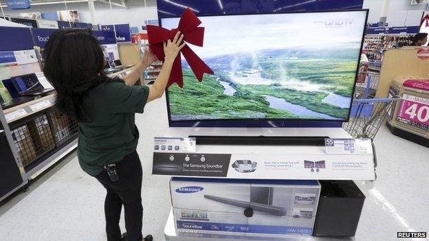 An employee adjusts a large ribbon on a television display at Wal-Mart as the store prepares for Black Friday in Los Angeles, California November 24, 2014