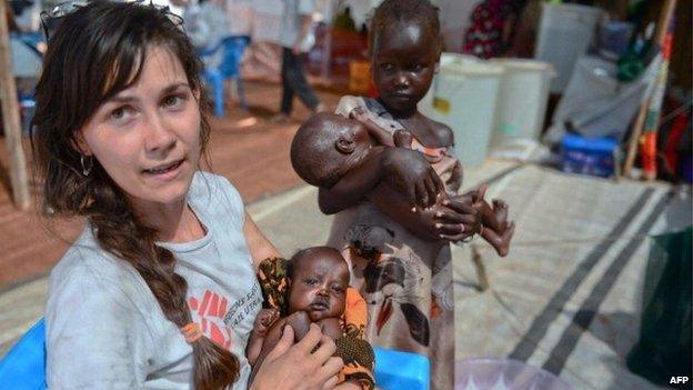 A Medecins Sans Frontieres (MSF) worker holds a South Sudanese baby while two little girls wait for treatment at the MSF hospital in Juba, on 22 February 2014