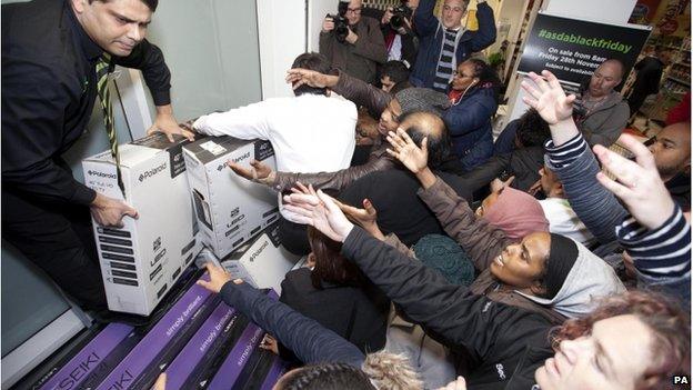 Staff handing out stock to a crowd of customers in Asda