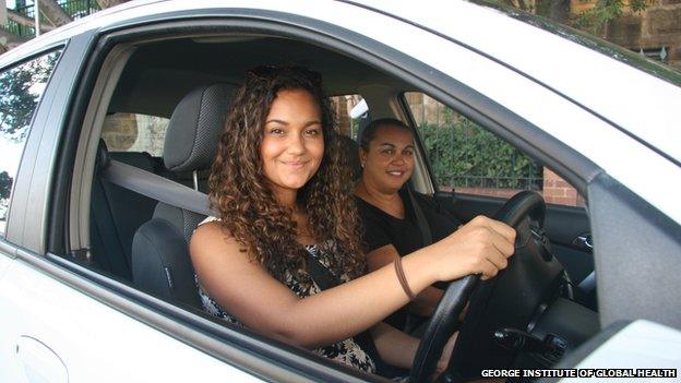 Two smiling Aboriginal women in front seats of white car