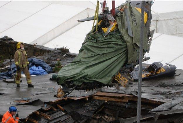 Rescuers lift the police helicopter wreckage from the roof of The Clutha pub