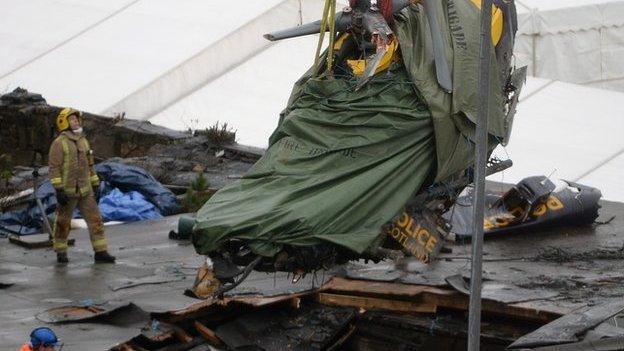 Rescuers lift the police helicopter wreckage from the roof of The Clutha pub