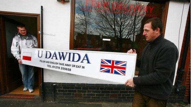 Polish immigrants Tomas Czekajlo (L) and Pawel Semen take delivery of the new sign at their new Polish take-away food shop, which they believe is the first in Britain on April 1, 2008 in Crewe, England