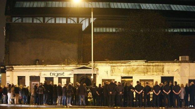 Members of the emergency services and the public hold a minute's silence outside the Clutha in Glasgow