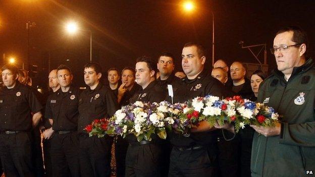 Members of the emergency services and the public hold a minute's silence outside the Clutha in Glasgow