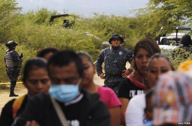 Police stand guard at a Mass for the dead students in Iguala, 29 November