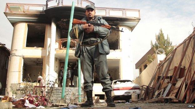 An Afghan security official stands guard at the office of a charity a day after an attack by Taliban militants, in Kabul (30 November 2014)