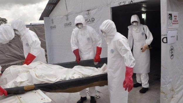 Health workers wearing Ebola protective gear remove the body of a man that they suspect died from the Ebola virus in Liberia