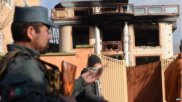 An Afghan policeman keeps watch outside the gate of a foreign compound following an attack by Taliban militants in Kabul on 30 November 2014.