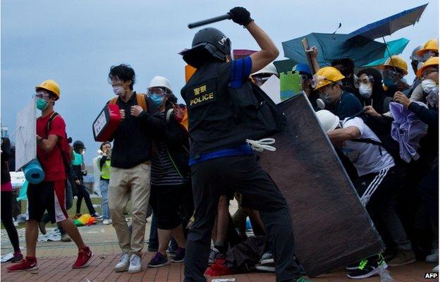 A policeman clashes with pro-democracy protesters during an operation to clear an occupied road near the government headquarters in the Admiralty district of Hong Kong early on 1 December 2014