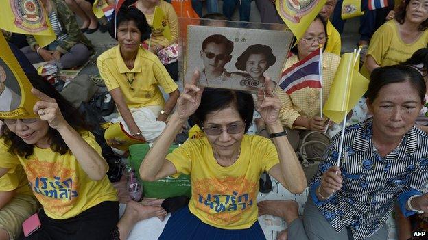 Well-wishers hold portraits of Thai King Bhumibol Adulyadej and Queen Sirikit as they wait for him to drive by in a motorcade in Bangkok (15 September 2014)