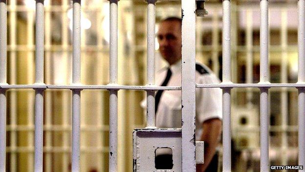 A prison officer seen through cell bars