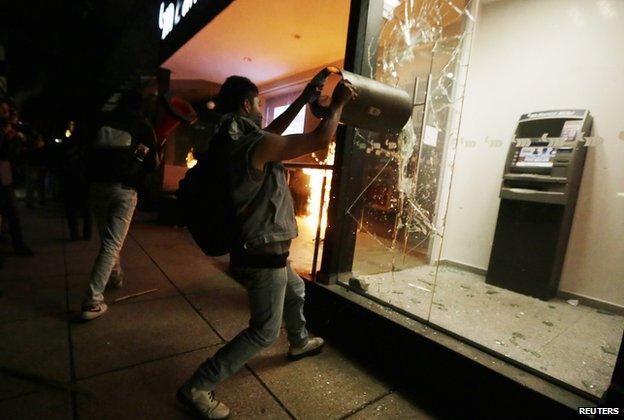 A demonstrator breaks the windows of an ATM facility during a protest in support of the 43 missing trainee teachers in Mexico City on 1 December, 2014