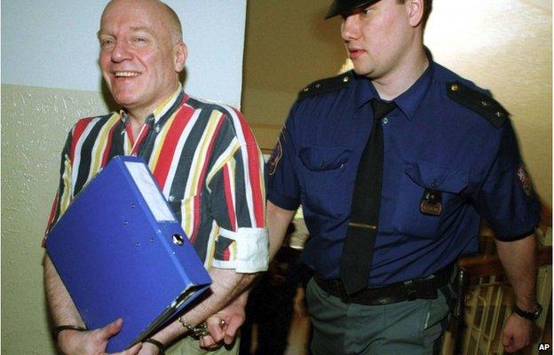 Chris Denning in handcuffs, being moved by a Czech police or court officer