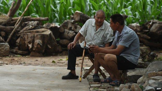 Two men sit near a corn field in Weijian village, in China's Henan province on July 30, 2014.