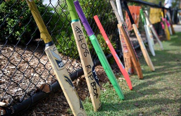 Cricket bats lean against the front fence of St Patrick's Primary School as a tribute to former student Hughes