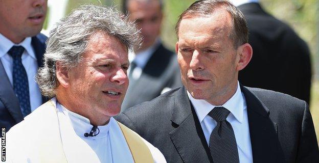 Prime Minister Tony Abbott is greeted by Father Michael Alcock