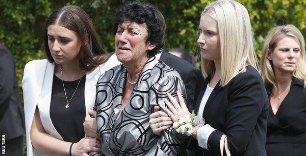 The mother of Hughes, Virginia, is comforted as she leaves the service