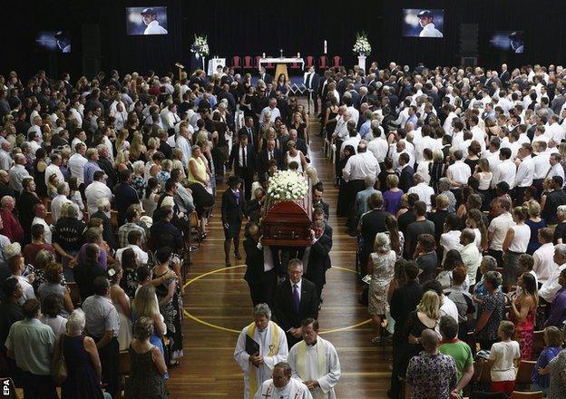 The coffin of Hughes is carried down the aisle at Macksville High School