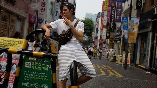 A man smokes on a street in the popular Myeongdong shopping area in Seoul on July 2, 2014