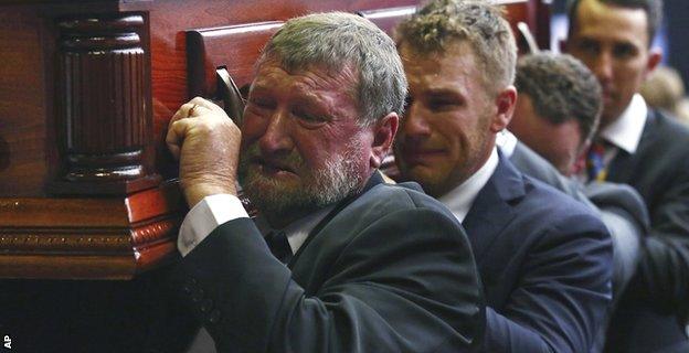 Gregory Hughes, father of Phillip, helps carry his son's coffin