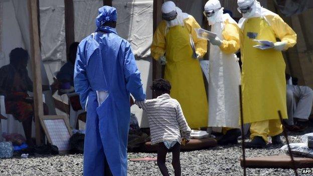 A nurse walking with a child in Monrovia, Liberia, on 27 September 2014