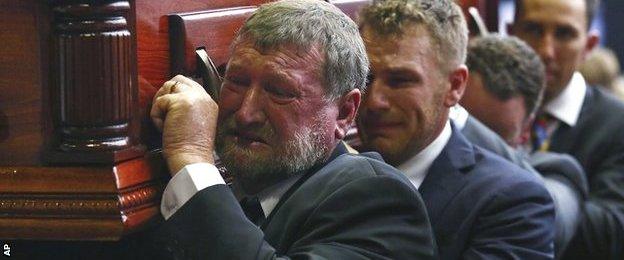 Gregory Hughes, father of Phillip, helps carry his son's coffin