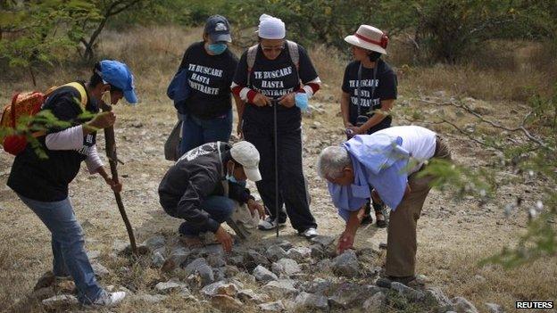 People with missing relatives search an area containing mass graves in La Joya, on the outskirts of Iguala, Guerrero state, on 29 November 2014.