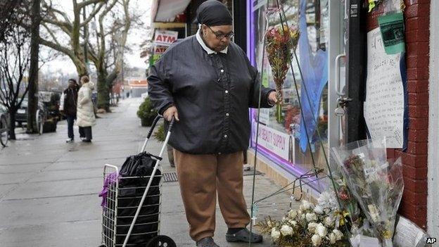 A woman, who did not want to give her name, places flowers at a memorial for Eric Garner near the site of his death in the borough of Staten Island Wednesday, Dec. 3, 2014., in New York