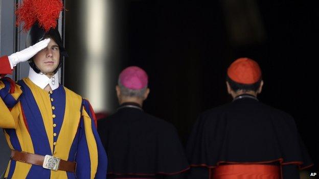 A Swiss Guard salutes two cardinals at the Vatican