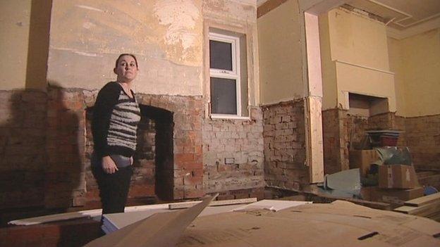 Lisa Moss standing in a derelict living and dining space in her house